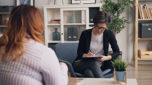 Two women engaged in a therapy session discussing mental health challenges.